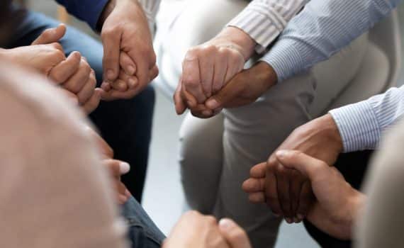 Hands holding in a prayer circle, used to explain a lifesaving liver transplant