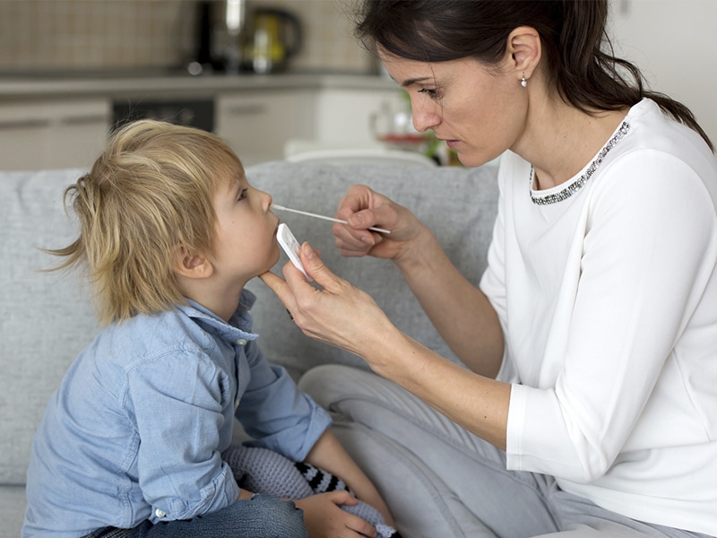 A woman administering an at-home test for COVID-19 to a child