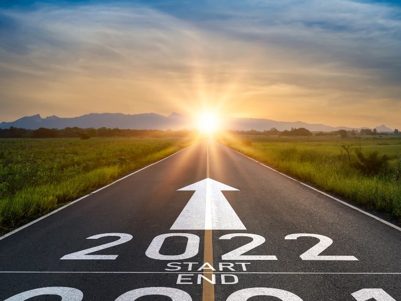 An inspirational photo of a sunset and "2022" written on a road, used to explain new year's resolutions