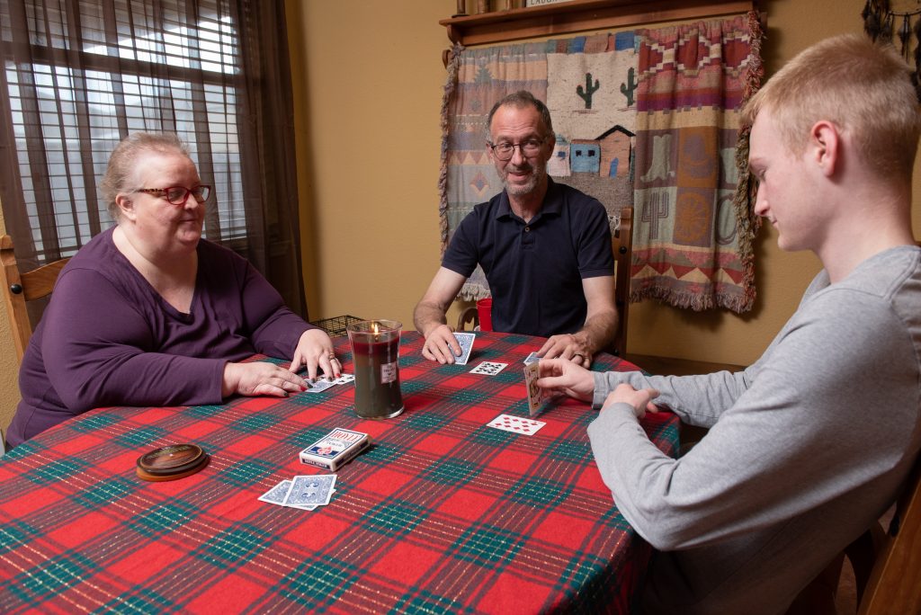 Roger Holcomb with his wife Shelly and son Morgan playing cards at a table