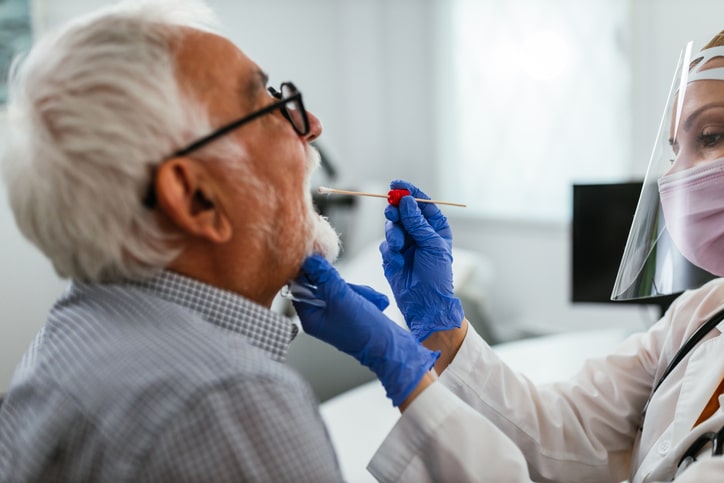 A medical professional administers at COVID-19 test to an older man