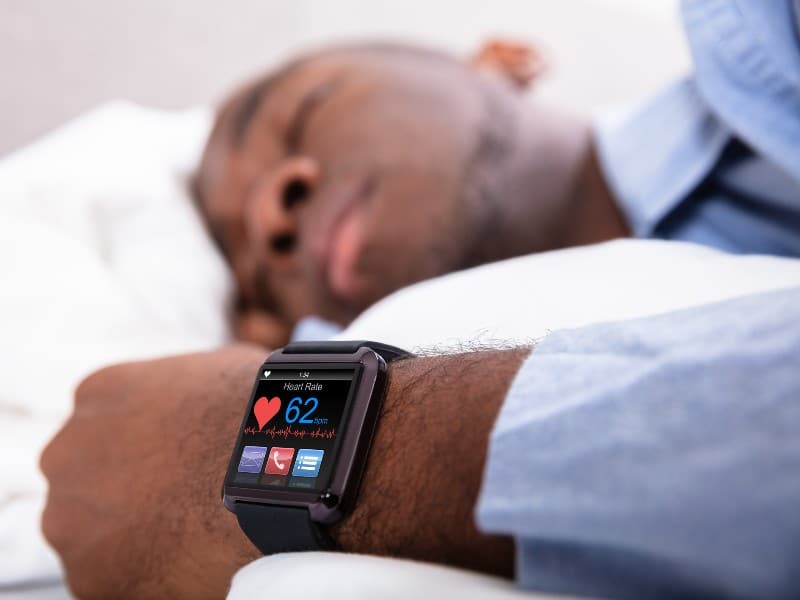 Man sleeping with the camera zoomed in on his smartwatch, used to explain sleep habits