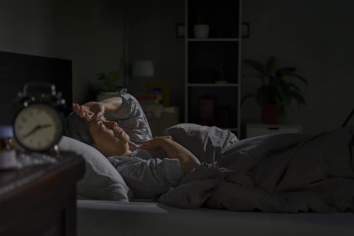 A photo of someone having sleep issues, looking up at the ceiling in a dark room