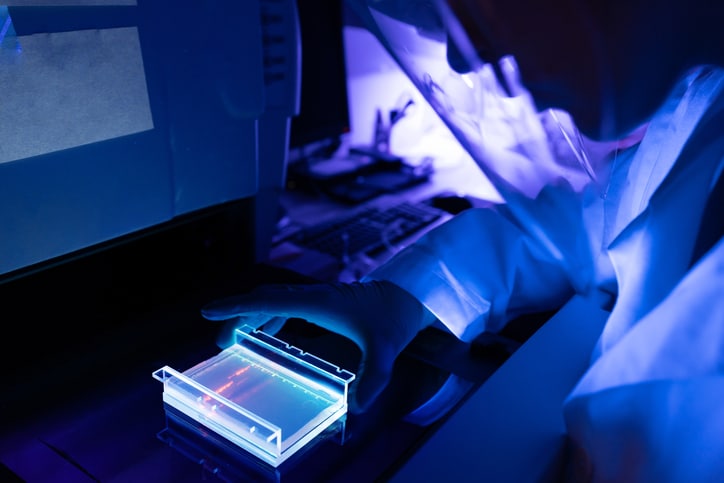 A dark photo of a laboratory technician looking at research