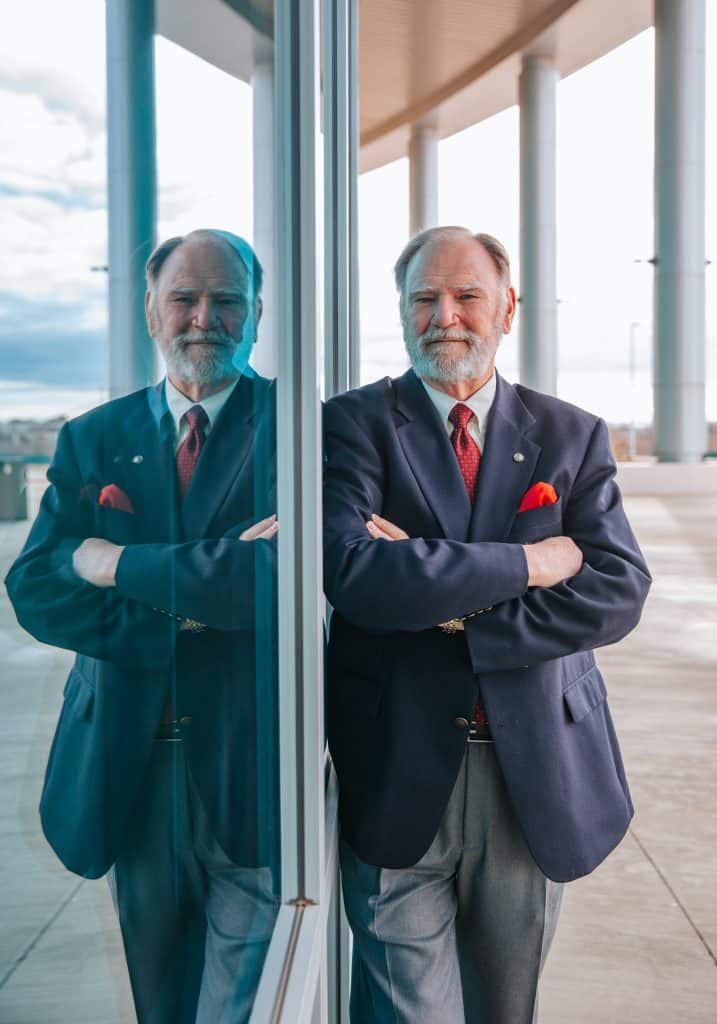 Claude Cunningham standing and leaning on the side of a building looking at the camera