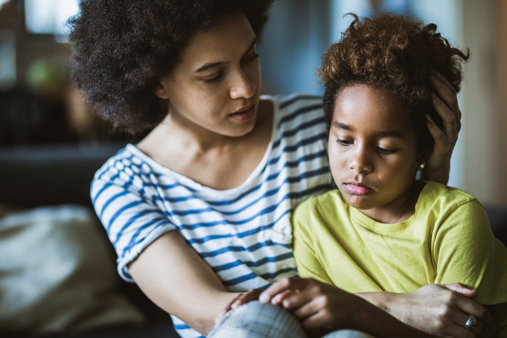 Woman looking concerned comforting and holding a younger child