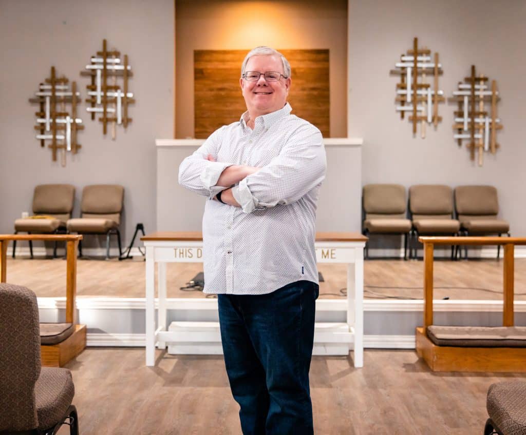 Chaplain Mark McDaniel smiling and photographed inside of a chapel