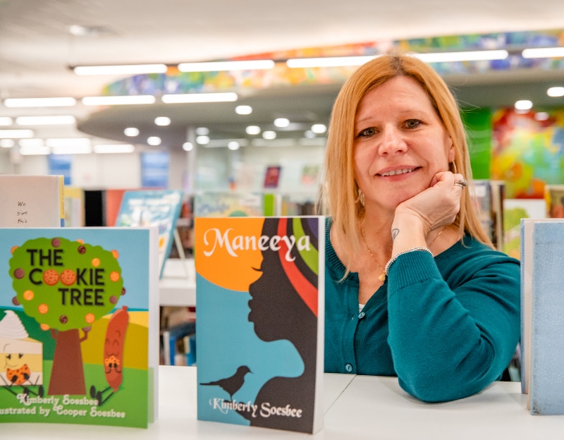 Kim Soesbee photographed in front of a few books standing upright