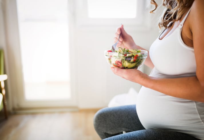 A pregnant woman eating a salad