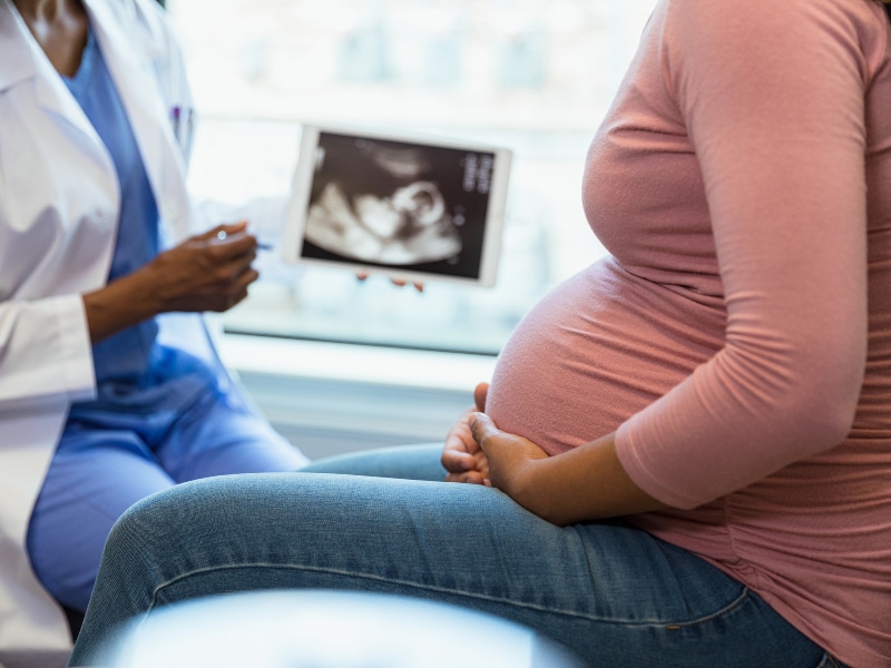 Stock image of a physician holding a sonogram and showing it to a pregnant woman holding her abdomen, used to explain preeclampsia