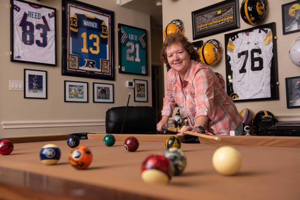 Tonya Dawson photographed while playing billiards surrounded by framed NFL jerseys