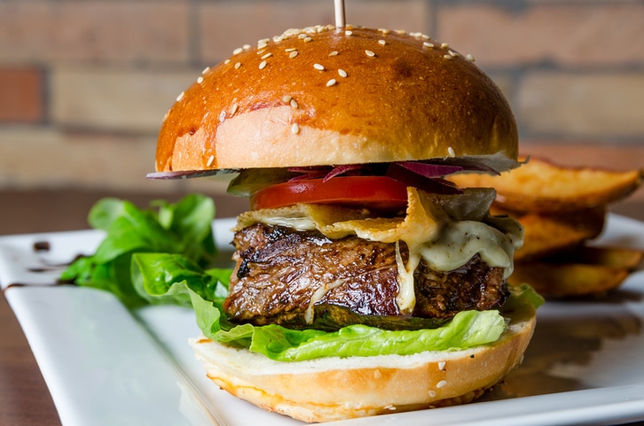 A photograph of a steak sandwich with lettuce, cheese, and tomato