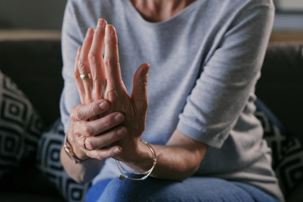 A woman holding the palm and wrist of her left hand, used to explain carpal tunnel syndrome