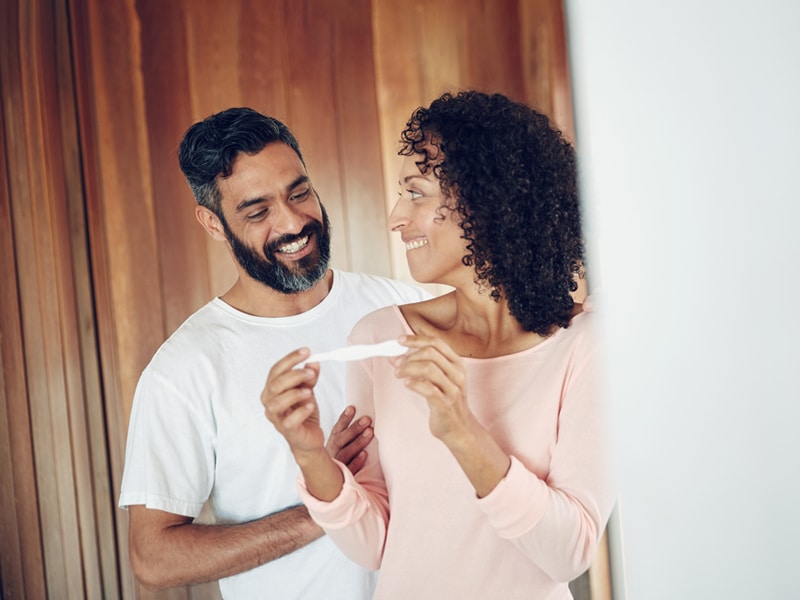 Two people looking at a pregnancy test, used to explain prenatal care