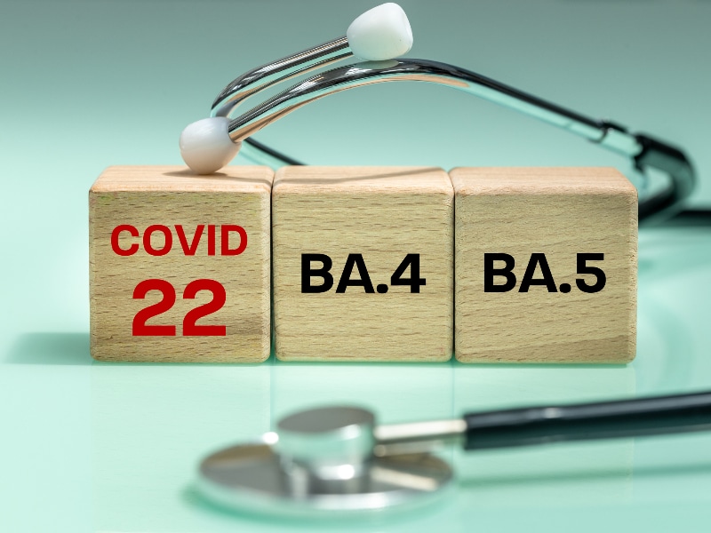Stock image of a stethoscope with three wooden blocks with the words COVID 22, BA.4, and BA.5 written on them