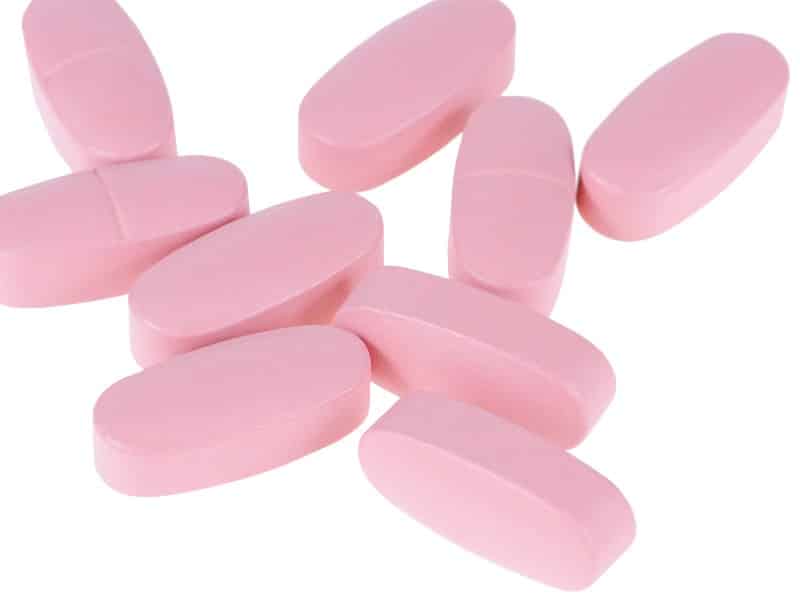 A collection of pink pills, used to explain Paxlovid