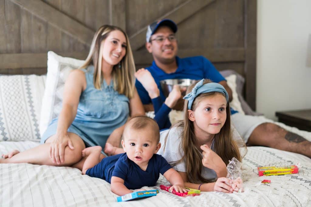 Alicia Fortner-Estrada, her husband, Jason, and their two children photographed sitting in bed, used to explain Alicia's time in the hospital after a postpartum hemorrhage