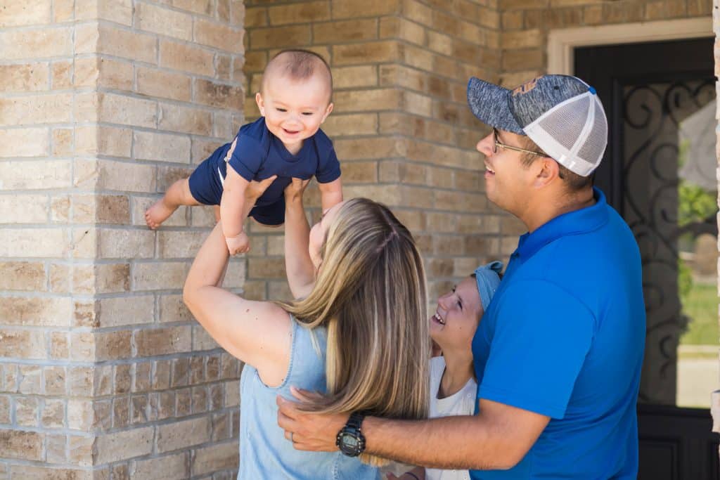 Alicia Fortner-Estrada, her husband, Jason, and their two children photographed, with Alicia holding 2-year-old Truitt in the air