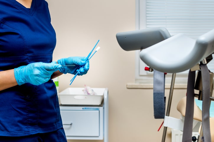 Stock image of a medical provider holding extended swabs in a medical room