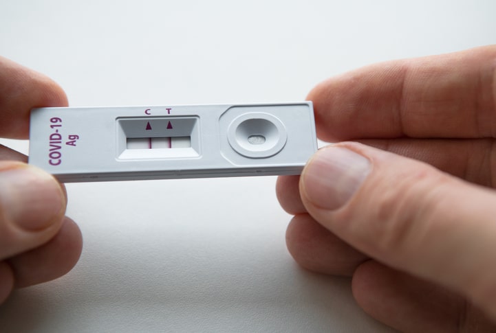 A COVID-19 test with two red lines under the C and T arrows, expressing a positive result