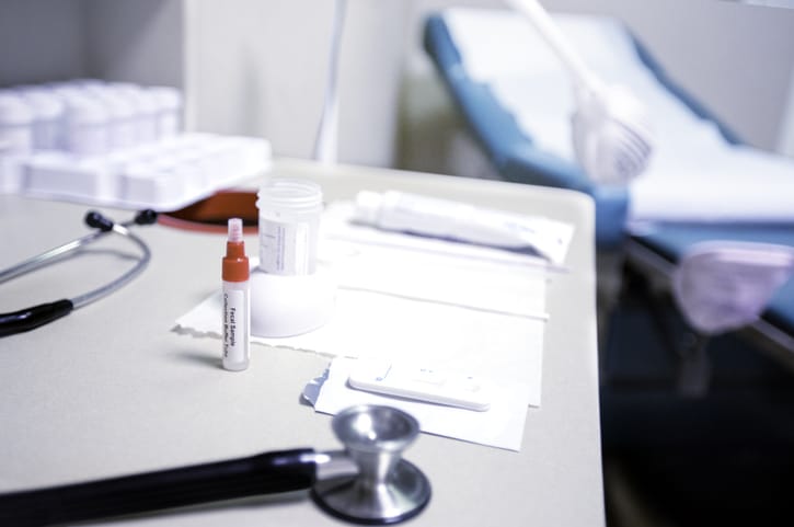 Stock image of medical supplies on a table in a medical room, including a stethoscope and paperwork