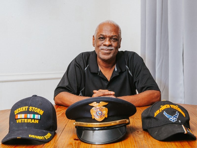 Waco police detective Dennis Taylor photographed with three of his police caps and smiling at the camera