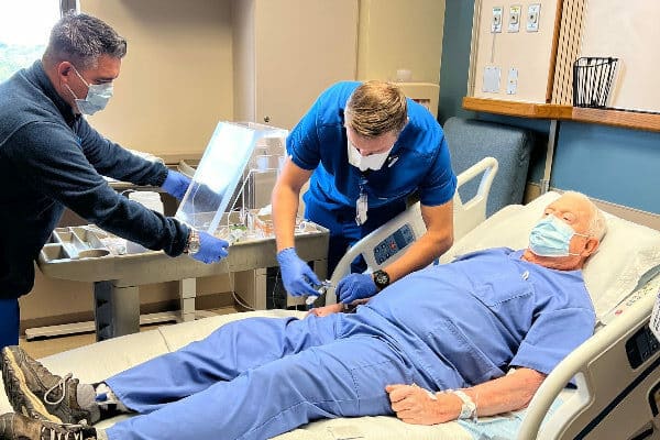 Two medical professionals helping provide care to a patient laying in a hospital bed