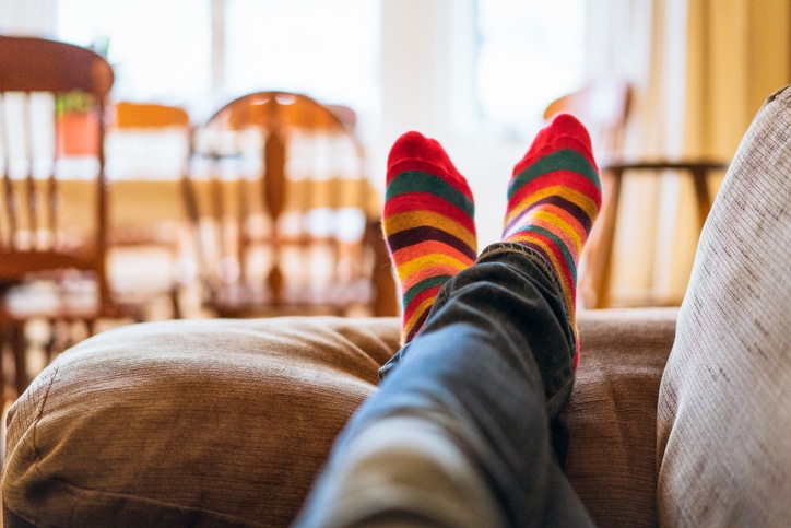 Two legs with the feet in focus, extended on a brown couch