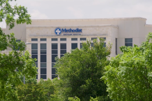 Photograph of a tan, multistory building with many windows and the logo for Methodist Southlake Hospital on it