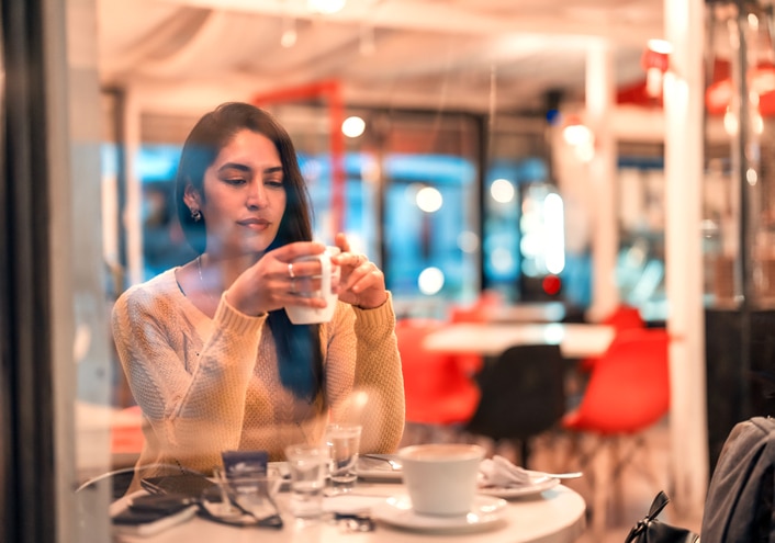 A woman holding a white mug sitting in a cafe
