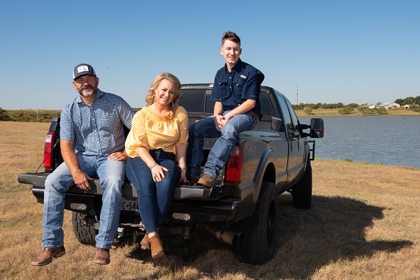 Garrett Blackmon photographed sitting on a truck with his mother and father