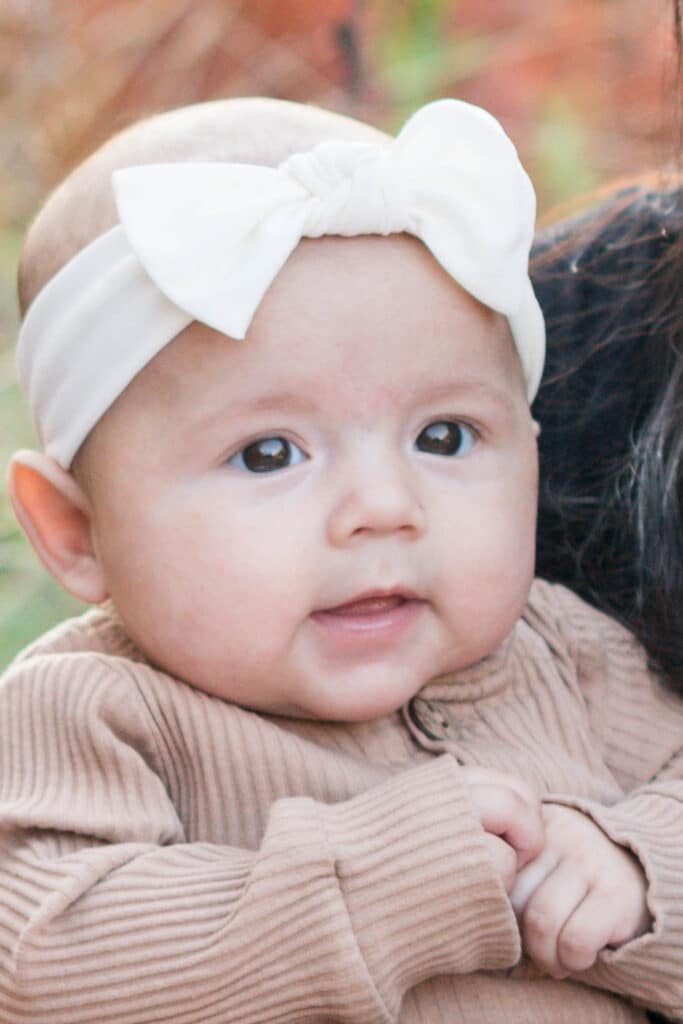 Baby Ruby wearing a white bow and looking off camera