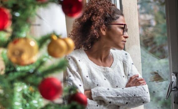 A woman looking out the window with holiday decorations in the foreground, used to explain coping with grief