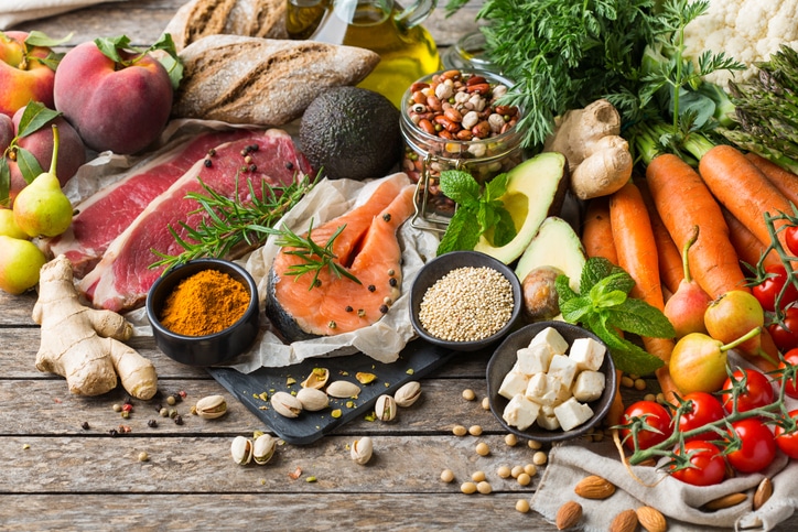 An array of healthy foods, including carrots, salmon, tofu, vegetables, spices, beans, and more