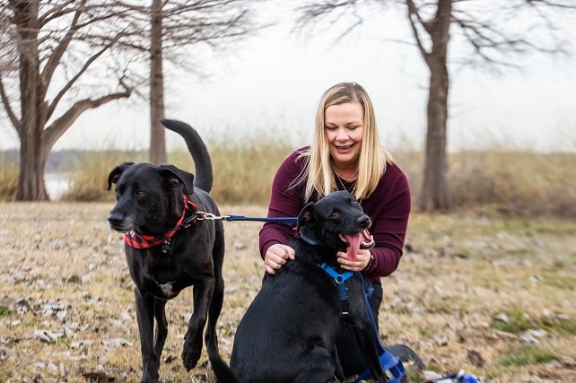Erin Sutton, a blond woman, photographed walking with her two black dogs, back on her feet after back surgery