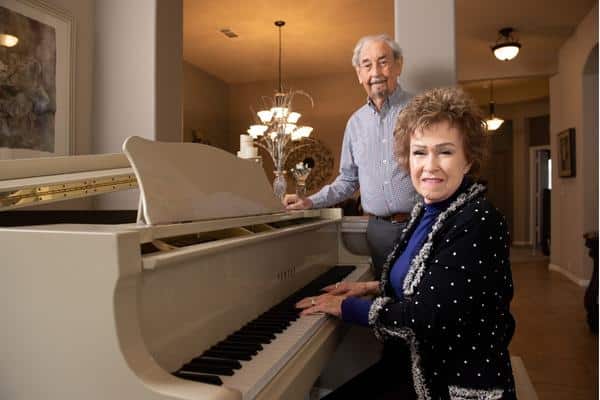 Lehman Myatt standing, and his wife Lois sitting, at a white baby grand piano