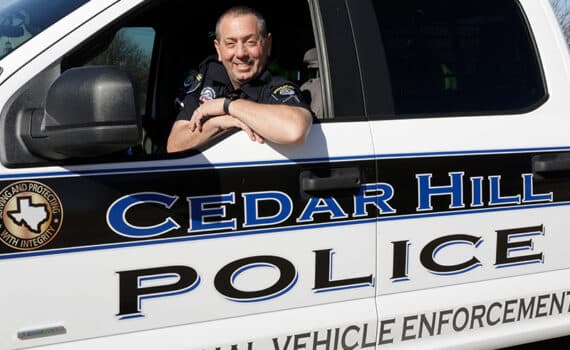 Army Staff Sgt. Jim Valenti sitting in a Cedar Hill police vehicle and smiling at the camera