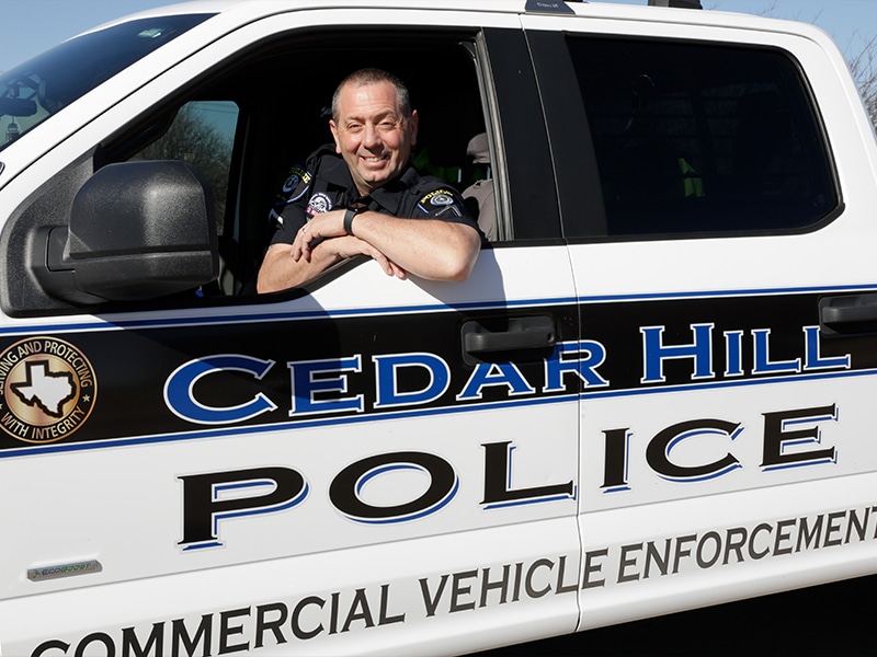 Army Staff Sgt. Jim Valenti sitting in a Cedar Hill police vehicle and smiling at the camera