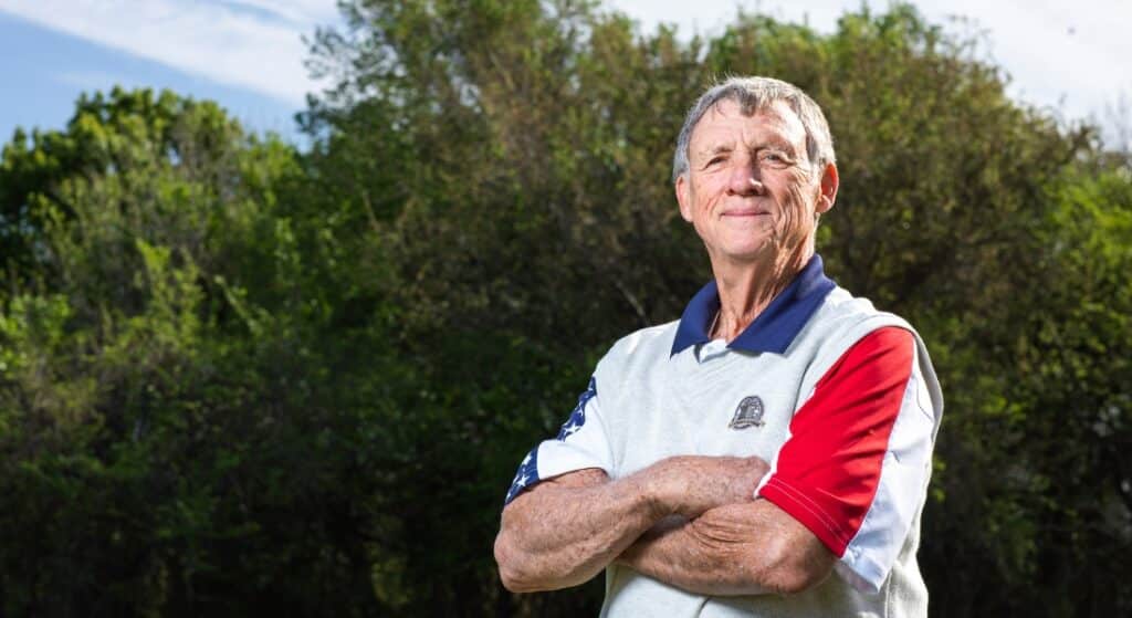 Security contractor Tom Eastman photographed in a collared golf shirt with trees in the background after hip and knee surgeries