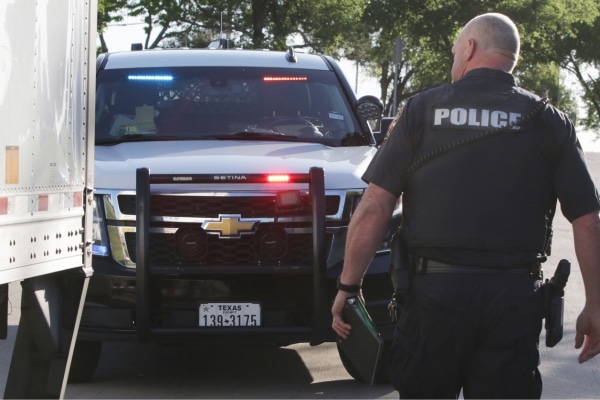 Officer Darren Burkhart with his back turned to the camera and a police SUV in the background 