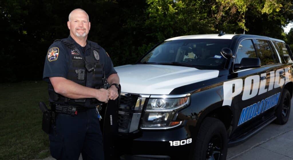 Officer Darren Burkhart posed next to a police SVU after he recovered from an infection