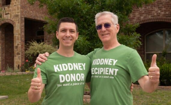 Doug and Collin Kidd smiling at the camera for a photo, wearing matching green shirts that say organ donor and organ recipient, respectively, used to explain this father's day story about kidney transplant.