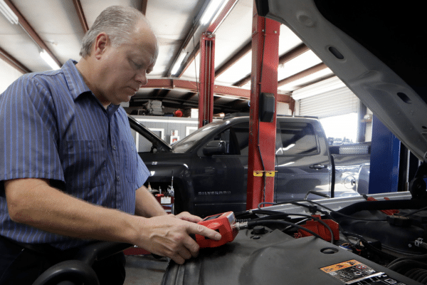 Roger Huseman, mechanic for the Ellis County police department, photographed while working on a vehicle in a garage