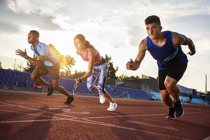 Three runners mid stride on a track and field ring