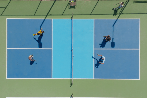 A view straight down of four people playing pickleball on a blue-and-green court