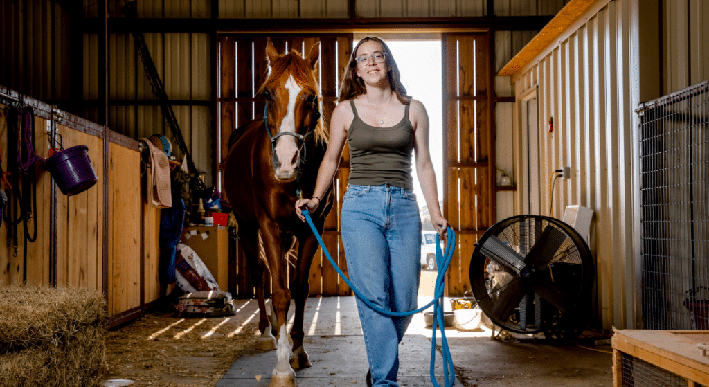Photograph of Kathryn Altman as a young adult next to a horse