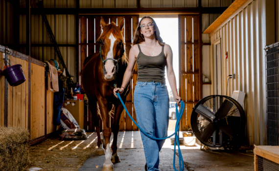 Photograph of Kathryn Altman as a young adult next to a horse