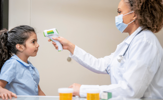 A medical provider checking a child's temperature, used to explain back to school wellness for children