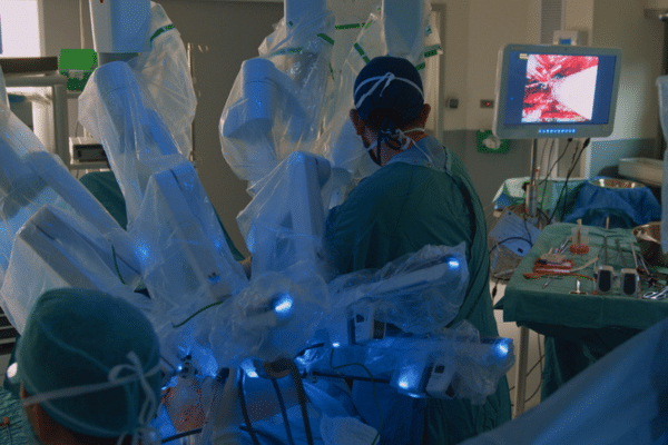 A photograph of a robotically assisted surgery with a robotic machine in the foreground
