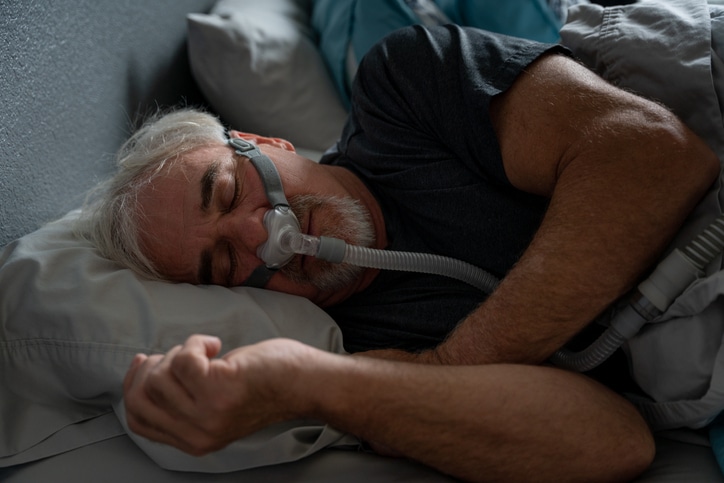 Man sleeping in bed with a CPAP machine